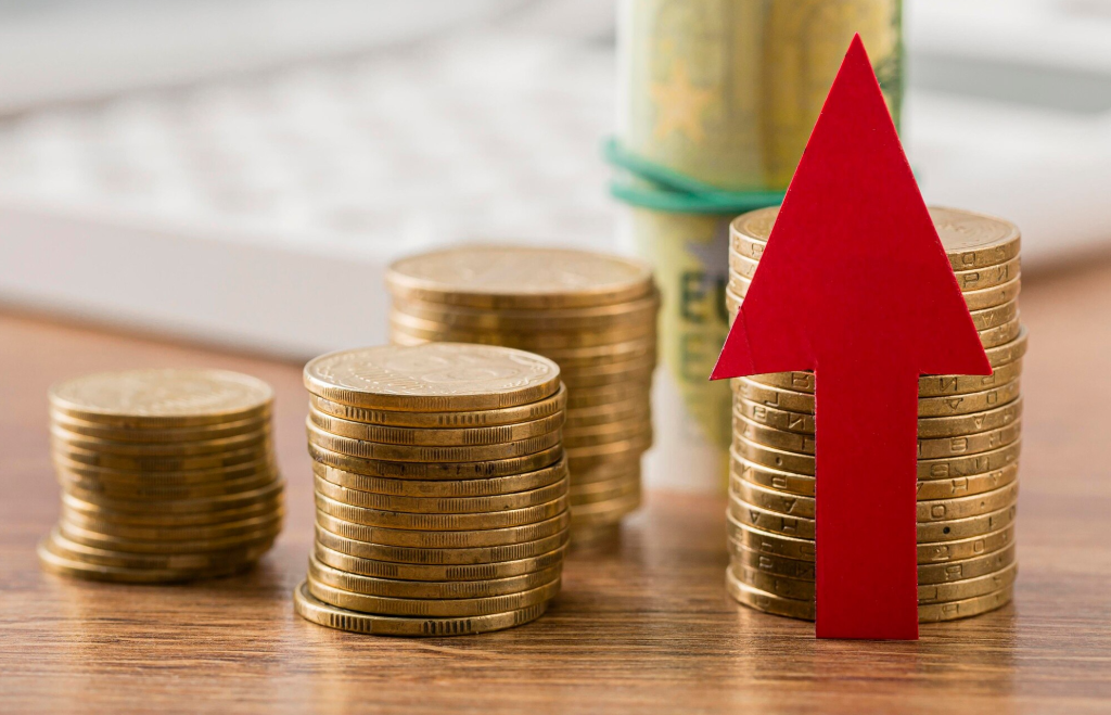 Moedas empilhadas com seta vermelha para o alto indicando bom capital de giro